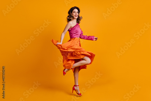 Fototapeta Naklejka Na Ścianę i Meble -  Merry european woman in bright skirt dancing. Studio shot of positive brunette girl.