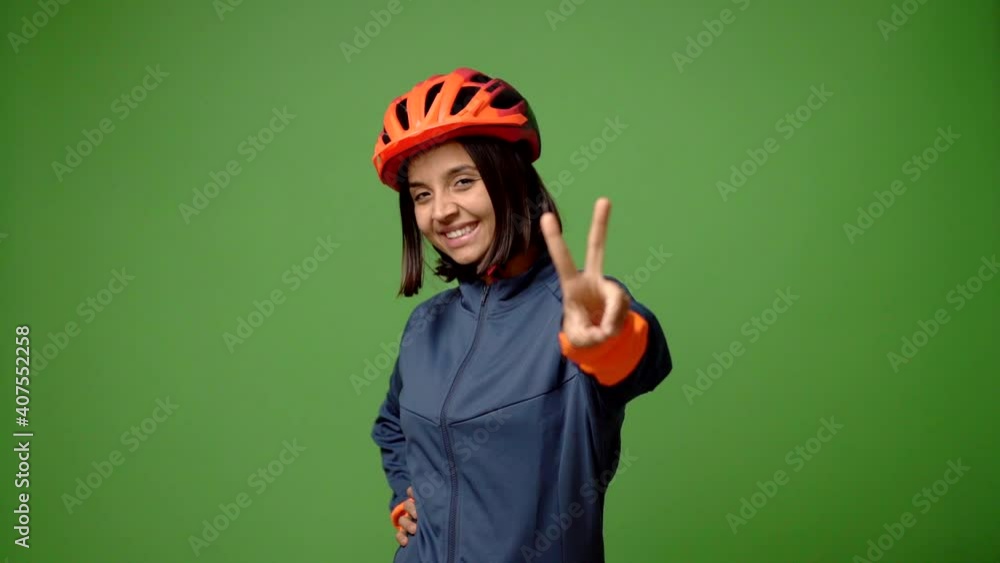 Young woman with cycling helmet smiling and showing victory sign with a cheerful face Young woman with cycling helmet smiling and showing victory sign with a cheerful face