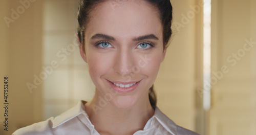 Beauty shot of young woman with blue eyes and perfect face skin just cleaned from impurities ready for moisturizing anti wrinkle day or night cream is smiling in camera isolated on golden background.
