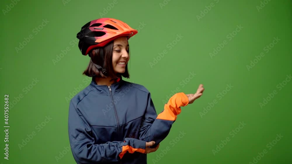 Young woman with cycling helmet extending hands to the side and inviting to come Young woman with cycling helmet extending hands to the side and inviting to come