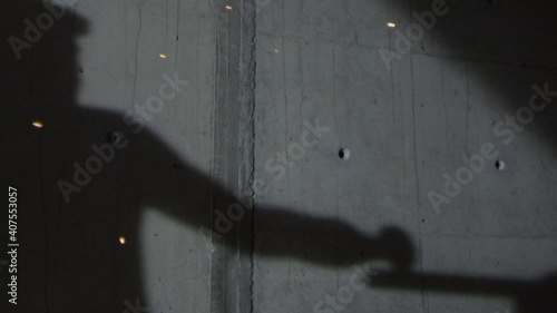 The shadow of a worker working with a sanding machine is reflected on the wall. Slow motion video. photo