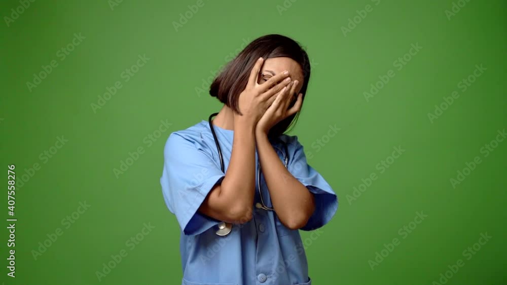 Woman with nurse uniform covering eyes by hands and looking through the fingers Woman with nurse uniform covering eyes by hands and looking through the fingers