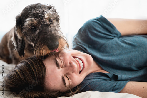 Фотография Happy woman playing with her dog inside home during lockdown isolation - Pet lic