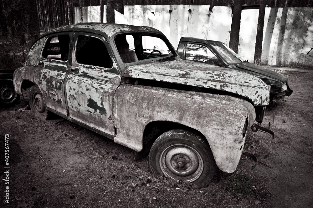 an old unnecessary non-working rusty car is standing in the forest