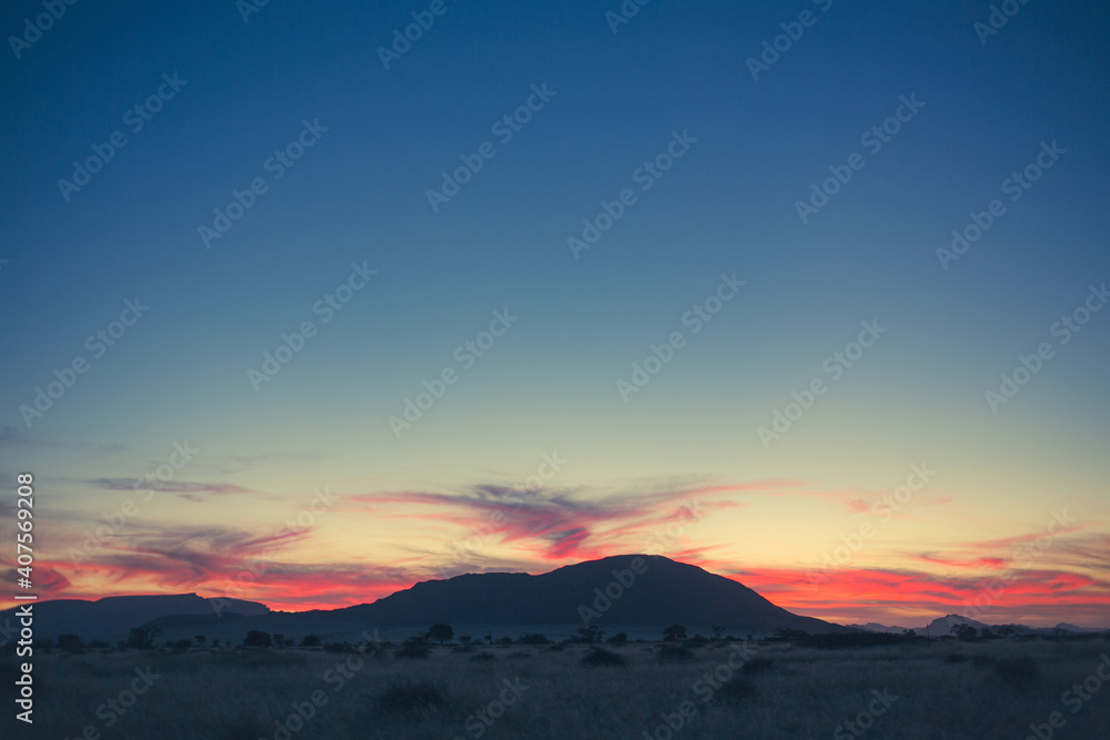 Pink clouds after sunset in empty Namibian landscape