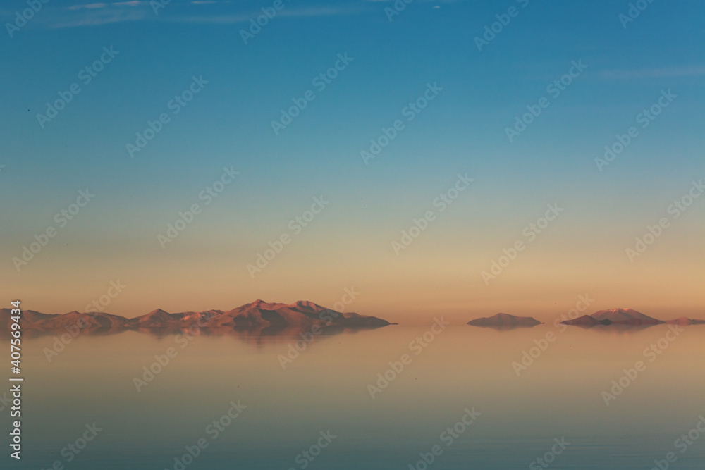 Mountain mirages with big sky in Bolivian salt flats