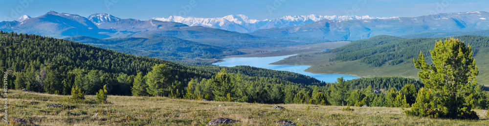 Mountain valley with a lake. Snow-capped peaks and blue sky.