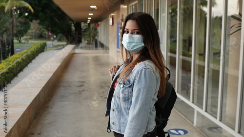 beautiful girl with a backpack on her back at school or college wearing a face mask to prevent virus in the new normal