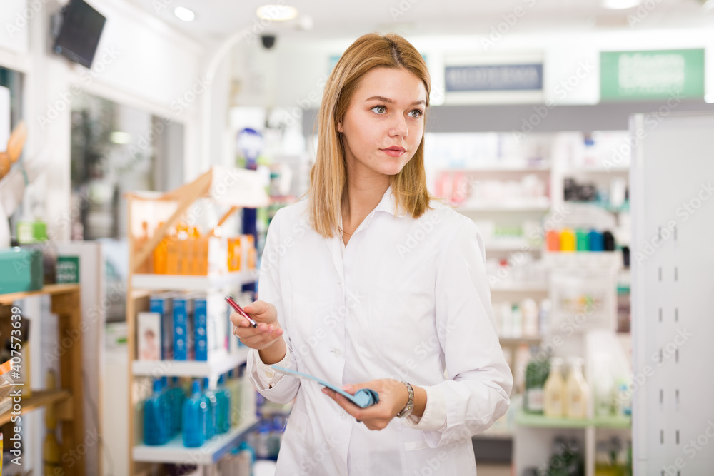 Pharmacist is writing down assortment of drugs in pharmacy. High quality photo