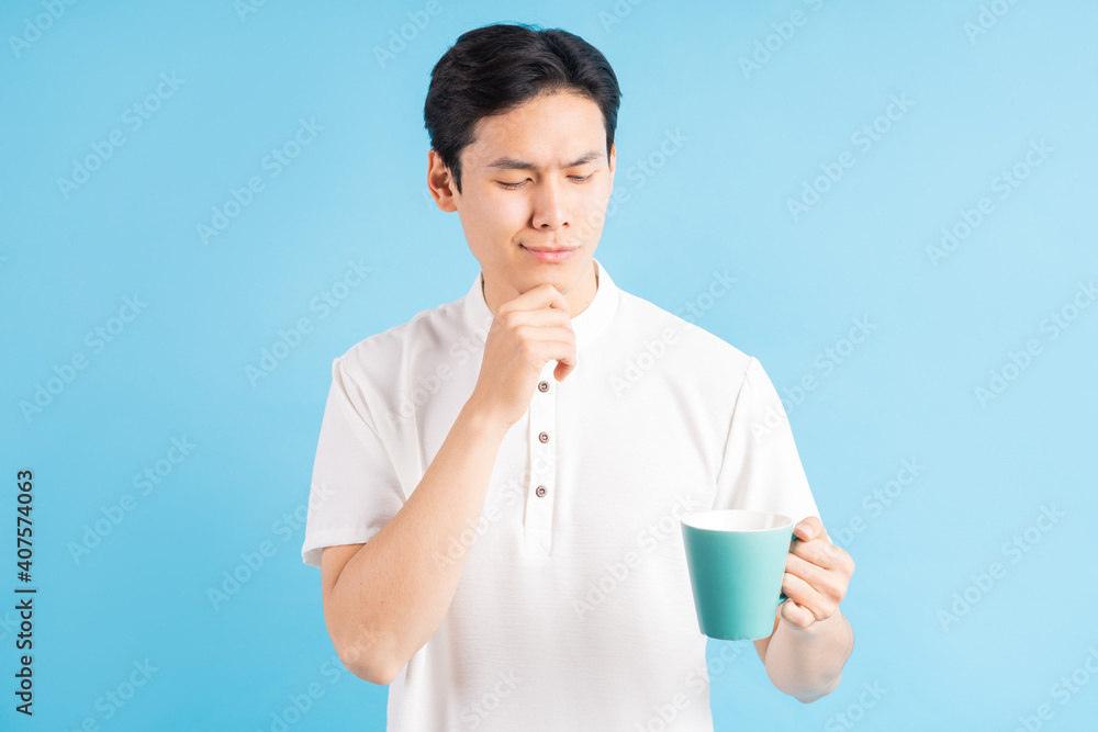 A photo of a handsome Asian man looking at a blue cup in his hand in a thoughtful manner
A photo of a handsome Asian man looking at a blue cup in his hand in a thoughtful manner