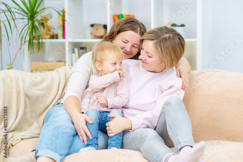 Happy daughter and smiling gay mothers in family home. Gay lesbian couple at home. Lesbian couple concept
