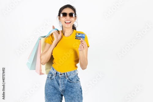 Smiling young Asian woman holding credit card and lot of shopping bag over white isolated background. Lifestyle, Consumerism, Sale and Shopping concept.