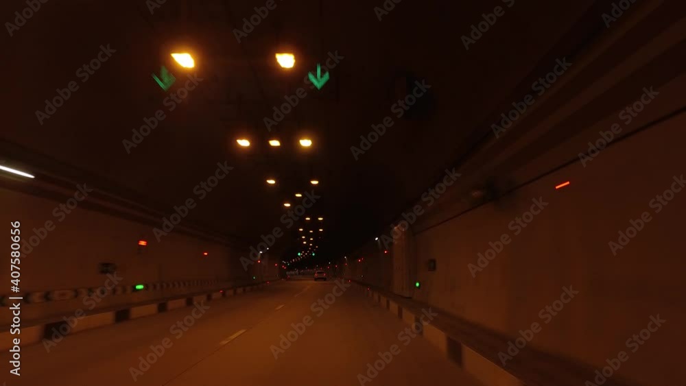 Car driving on city road through dark illuminated tunnel Car driving on city road through dark illuminated tunnel