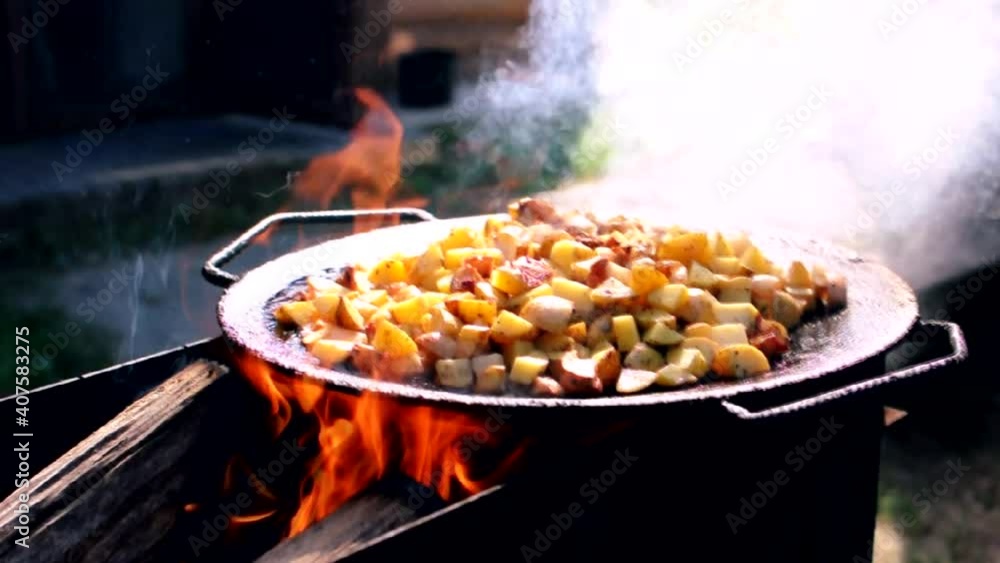 Cooking fried potatoes with lard over the fire.General plan,reverse
