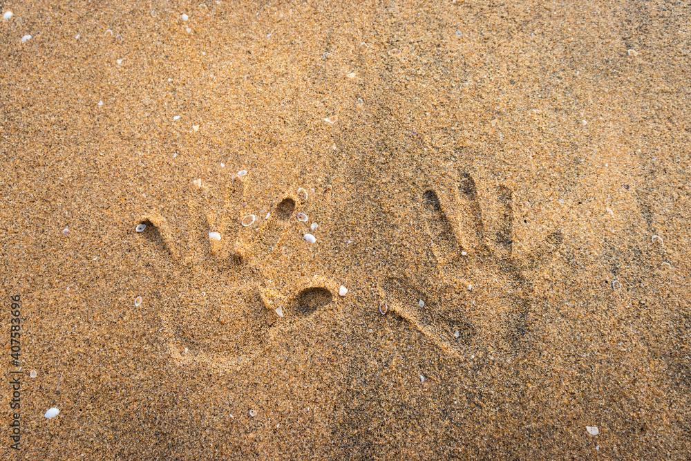 Couple hand prints on yellow sandy beach showing love for each other and the nature