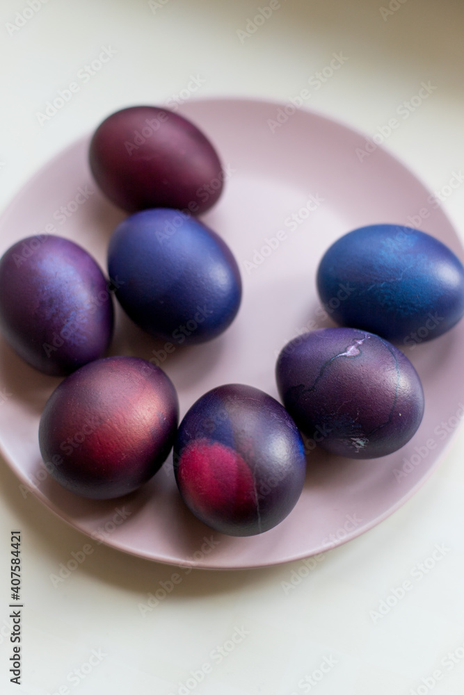 Painted blue and purple Easter eggs on a textured background. Easter eggs on a plate. Painted blue and purple Easter eggs on a textured background. Easter eggs on a plate.