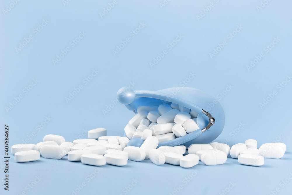 White tablets falling out of blue coins purse, drugs and medicine safety consumption and cost of medical care or insurance coverage concept with copy space on blue background. Healthcare and pharmacy White tablets falling out of blue coins purse, drugs and medicine safety consumption and cost of medical care or insurance coverage concept with copy space on blue background. Healthcare and pharmacy