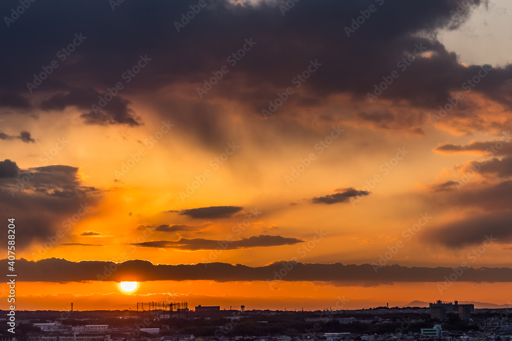 地平線と雲の間から顔を出す太陽、夕焼けのある風景