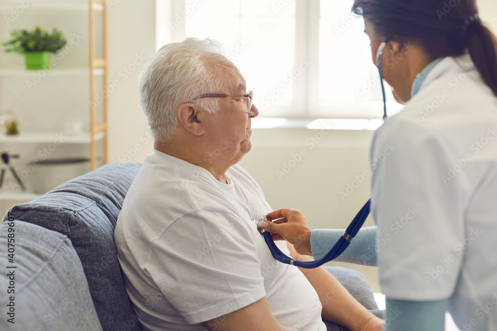 Obraz premium Doctor listening to the heart and breathing of an older man through a stethoscope on his chest.