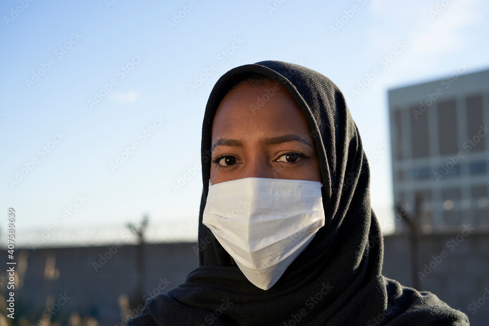 Close-up of face of a young Muslim girl with hijab and mask looking at the camera. Close-up of face of a young Muslim girl with hijab and mask looking at the camera.