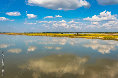 clear blue sky with many small cloud patch and river water reflection © explorewithinfo