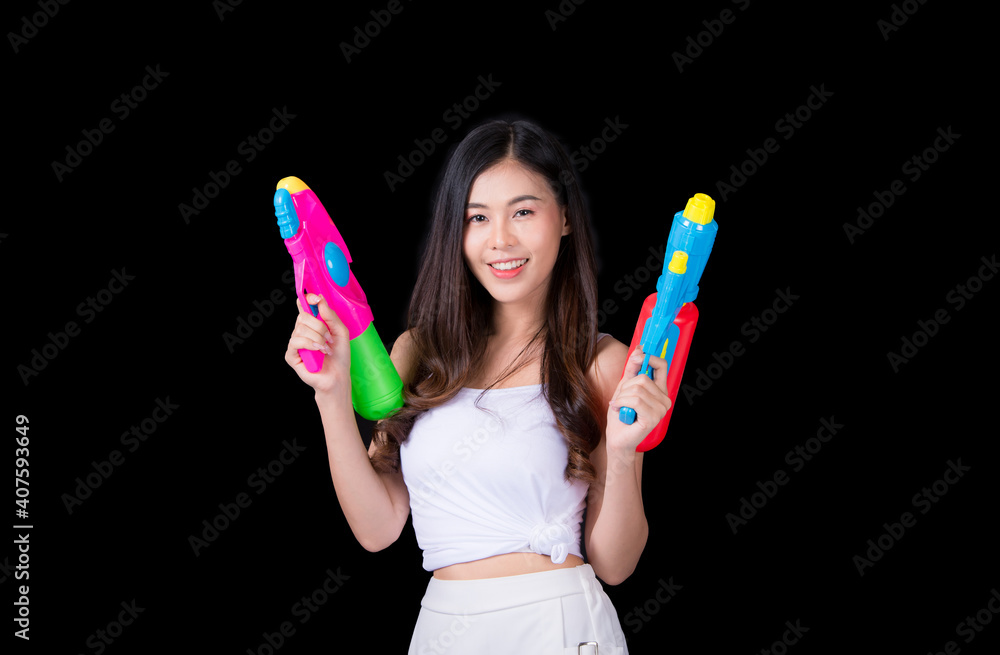 Young happy beauty Asian woman holding plastic water gun at Songkran festival, Thailand. Thai New Year's Day. Isolated on black background. Young happy beauty Asian woman holding plastic water gun at Songkran festival, Thailand. Thai New Year's Day. Isolated on black background.