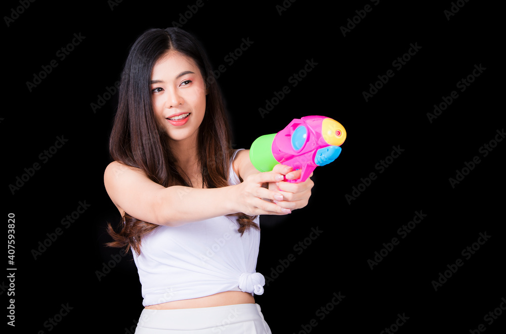 Young happy beauty Asian woman holding plastic water gun at Songkran festival, Thailand. Thai New Year's Day. Isolated on black background. Young happy beauty Asian woman holding plastic water gun at Songkran festival, Thailand. Thai New Year's Day. Isolated on black background.