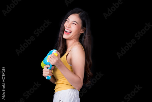Portrait cheerful young asian woman holding plastic water gun Smiling and having fun playing in the water Songkran festival  Thailand. isolated on black background. Thai New Year s Day.
