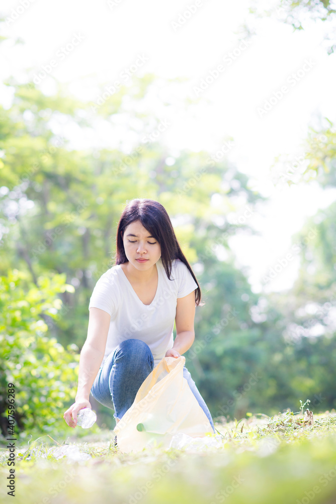 Asian Young woman hand picking up garbage plastic for cleaning at park.Environmental conservation. Asian Young woman hand picking up garbage plastic for cleaning at park.Environmental conservation.