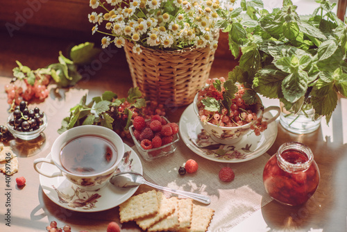 summer breakfast. a summer garden still life with a mug of tea, wildflowers and berries. garden aesthetics