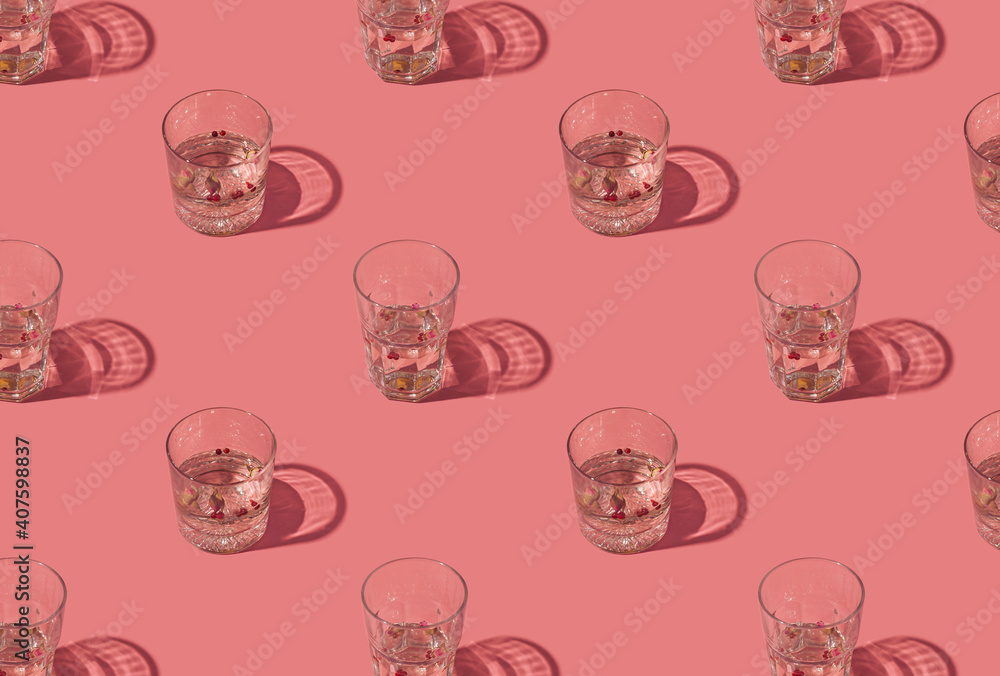 Gin and tonic crystal glasses garnished with rose buds and red peppercorns on a pastel pink background. Creative summer drink pattern. Gin and tonic crystal glasses garnished with rose buds and red peppercorns on a pastel pink background. Creative summer drink pattern.