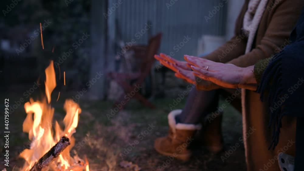 Close-up unrecognizable women legs sitting in front of bonfire warming hands. Wildlife, warm concept. Close-up unrecognizable women legs sitting in front of bonfire warming hands. Wildlife, warm concept.