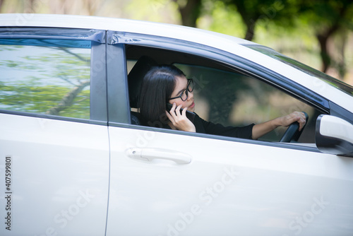 The car is broken and parked on the side of the road, the stressful young woman is calling the car mechanic with a mobile phone.