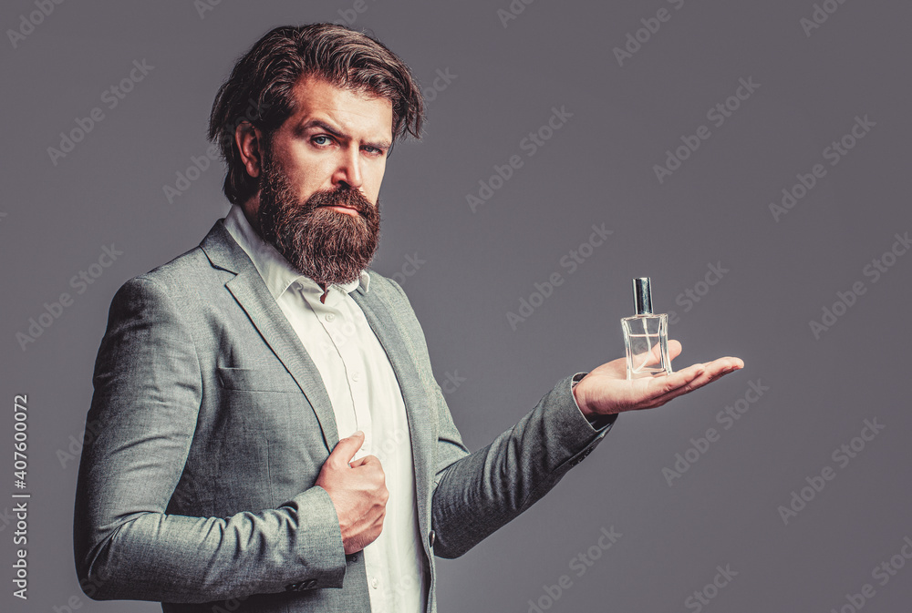 Male holding up bottle of perfume. Man perfume, fragrance. Perfume or  cologne bottle and perfumery, cosmetics, scent cologne bottle, male holding  cologne. Masculine perfume, bearded man in a suit Stock Photo