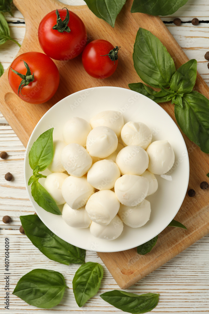 Concept of tasty eating with bowl of mozzarella cheese on white wooden background