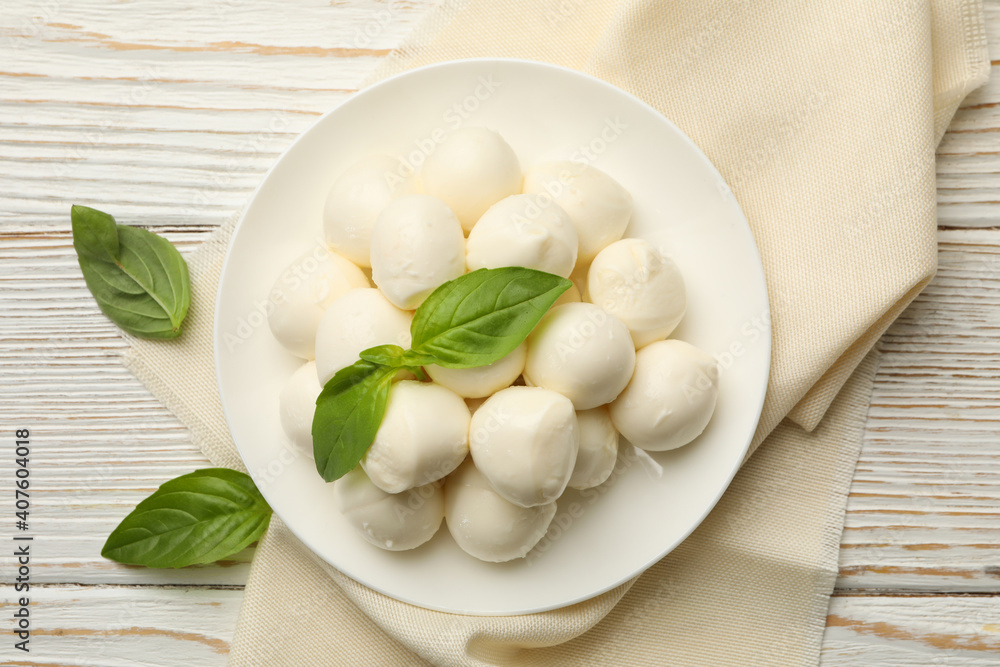 Kitchen towel with plate with mozzarella and basil on wooden background Kitchen towel with plate with mozzarella and basil on wooden background