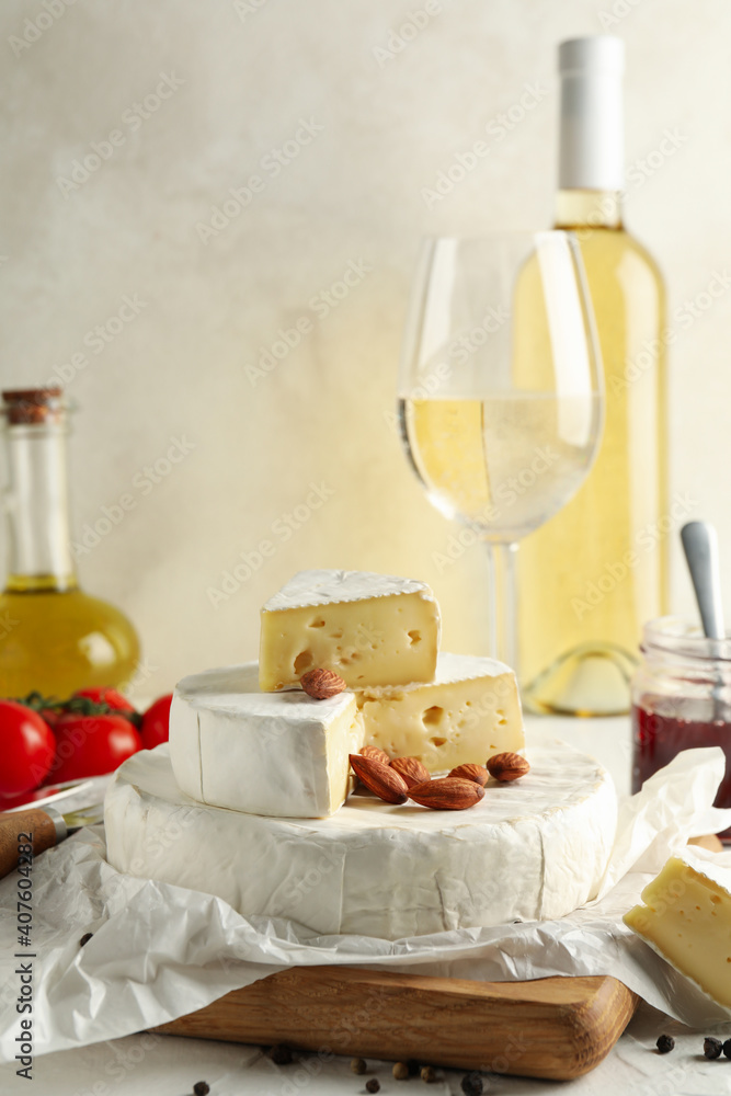 Concept of tasty eating with camembert, hazelnut and wine on white table