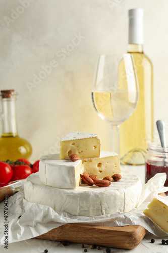 Concept of tasty eating with camembert, hazelnut and wine on white table