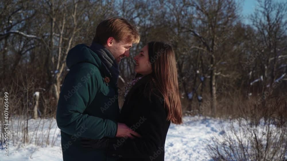 Young Lovers Stand and Hug in the Winter Forest. Lovely Man and Woman in an Embrace on the background of a Snowy Grove. Love and Family. Slow motion. High quality FullHD footage Young Lovers Stand and Hug in the Winter Forest. Lovely Man and Woman in an Embrace on the background of a Snowy Grove. Love and Family. Slow motion. High quality FullHD footage