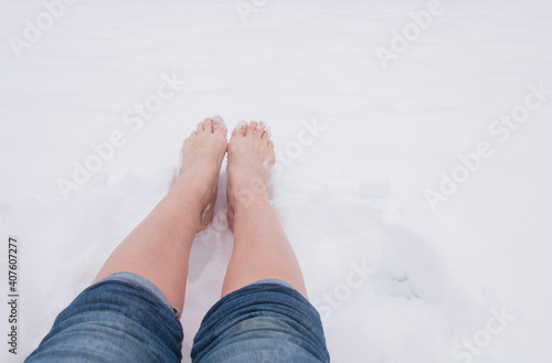 Girl barefoot on white cold snow in winter on a frosty day. Health hardening concept, protection against covid-19 virus © Inga
