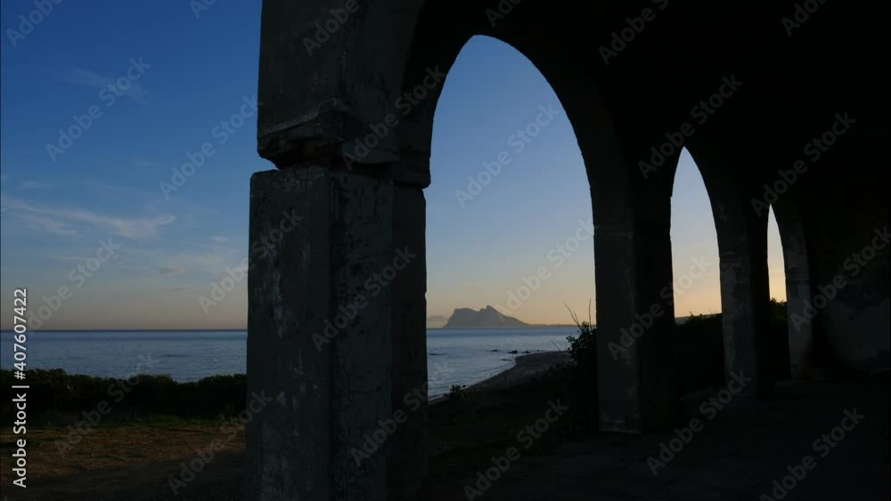 Old arch building on Torrecarbonera beach, Punta Mala, Andalusia Spain. Clouds moving over sea and british Gibraltar rock on horizon, time lapse Old arch building on Torrecarbonera beach, Punta Mala, Andalusia Spain. Clouds moving over sea and british Gibraltar rock on horizon, time lapse
