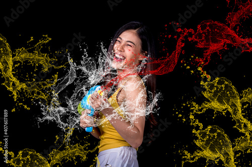 Portrait cheerful young asian woman holding plastic water gun Smiling and having fun playing in the water Songkran festival, Thailand. isolated on black background. Thai New Year's Day.