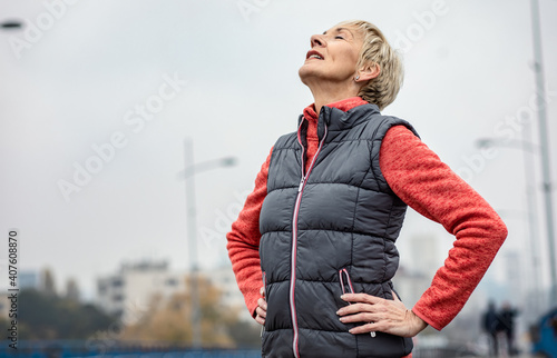 Billede på lærred Active senior woman stretches her muscles before running through the city during the day