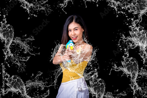 Portrait cheerful young asian woman Wearing a yellow tank top ,holding plastic water gun Smiling and having fun playing in the water Songkran festival, Songkran Thailand. isolated on black background.