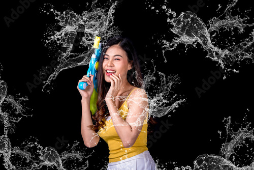 Portrait cheerful young asian woman Wearing a yellow tank top ,holding plastic water gun Smiling and having fun playing in the water Songkran festival, Songkran Thailand. isolated on black background.