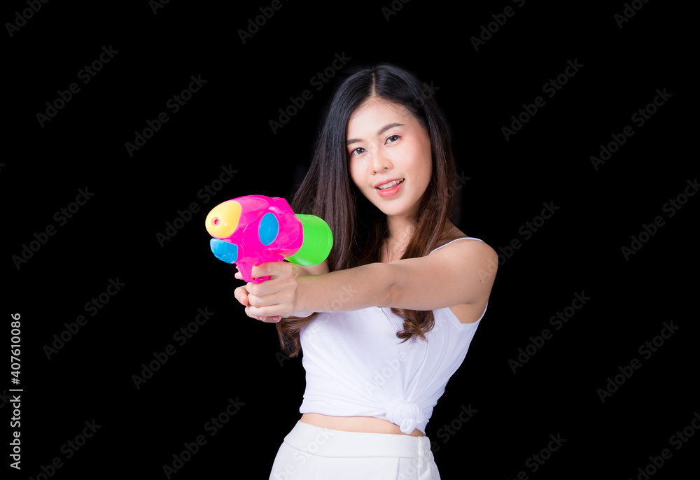 Portrait cheerful young asian woman Wearing a yellow tank top ,holding plastic water gun Smiling and having fun playing in the water Songkran festival, Songkran Thailand. isolated on black background. Portrait cheerful young asian woman Wearing a yellow tank top ,holding plastic water gun Smiling and having fun playing in the water Songkran festival, Songkran Thailand. isolated on black background.