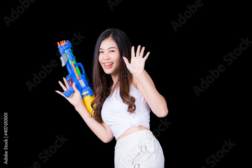 Portrait cheerful young asian woman Wearing a yellow tank top ,holding plastic water gun Smiling and having fun playing in the water Songkran festival, Songkran Thailand. isolated on black background.