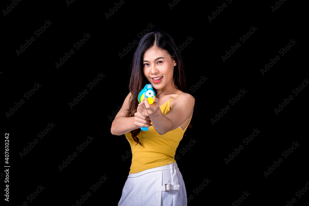 Portrait cheerful young asian woman Wearing a yellow tank top ,holding plastic water gun Smiling and having fun playing in the water Songkran festival, Songkran Thailand. isolated on black background. Portrait cheerful young asian woman Wearing a yellow tank top ,holding plastic water gun Smiling and having fun playing in the water Songkran festival, Songkran Thailand. isolated on black background.