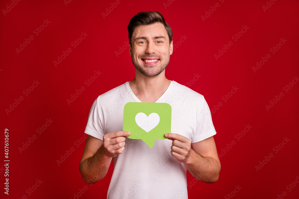 Photo portrait of happy guy showing like green card with heart smiling isolated vivid red color background Photo portrait of happy guy showing like green card with heart smiling isolated vivid red color background
