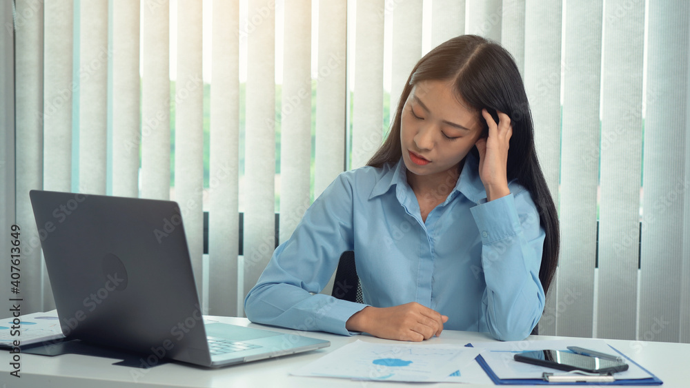 Asian woman manager is stressed and has a headache about faulty work documents at her office. Asian woman manager is stressed and has a headache about faulty work documents at her office.